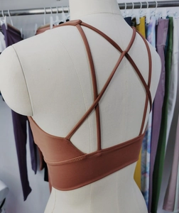 Detail of high-elasticity sports bra featuring criss-cross back straps in rust red color