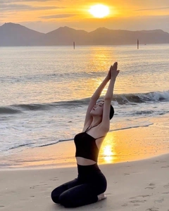 Vue latérale du débardeur yoga noir dos nu et legging taille haute sur la plage au coucher du soleil