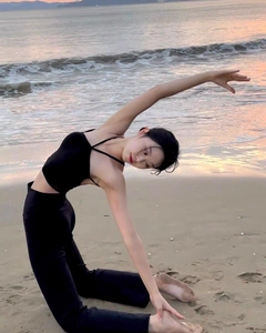 Détail du haut de yoga noir à bretelles croisées et legging taille haute au coucher du soleil