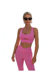 Detail of pink high-elastic yoga set showing cutout sports bra and crisscross waist leggings