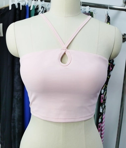 Détail du haut de yoga rose clair avec découpe goutte et design à licou croisé