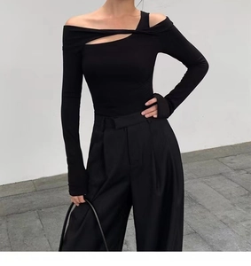 Detail of black off-the-shoulder yoga top with asymmetrical cutout and slim fit sleeves