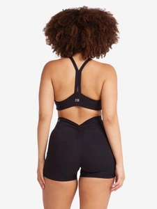 Détail du soutien-gorge de sport noir et du short froncé à taille haute avec logo