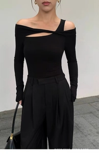 Detail of slim fit black yoga top featuring asymmetrical cut-out shoulder and long sleeves