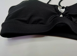 Detail of black sports bra with silver metal ring connector and reinforced stitching