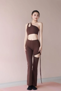 Detail of dark brown one-shoulder yoga jumpsuit with asymmetrical cutouts and ribbons