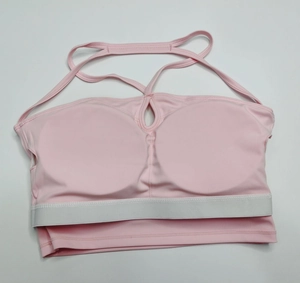 Détail d'un soutien-gorge de sport rose avec bretelles croisées et bande élastique blanche