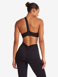 Détail de la brassière de sport asymétrique et du legging avec taille en V et fronces
