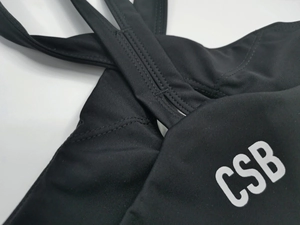 Coutures plates détaillées sur le brassière de sport noire avec logo CSB