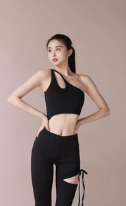 Detail of black one-shoulder yoga jumpsuit featuring waist cutout and leg lace-up design