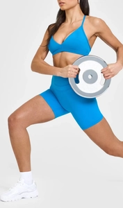 Elektroblaues Sport-BH und Shorts Set gezeigt in Bewegung mit Gewichtsscheiben für Fitness