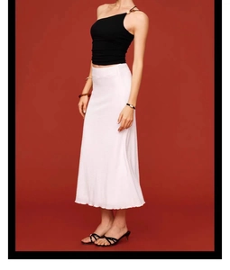 Detail of the elegant white midi skirt featuring a subtle horizontal textured fabric finish
