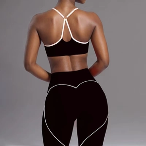 Detail of cross back pink straps and heart-shaped lifting seam on black yoga leggings