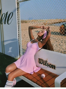 Detalle del vestido de tenis rosa con cuello en V y bordes blancos en la cancha de tenis