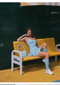 Detalle de vestido de tenis azul cielo con tirantes en V en una cancha de tenis exterior