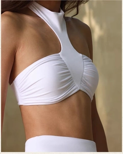 Detail showing white halter neck sports bra with pleated design and high elasticity fabric