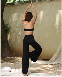 Detail of black backless yoga top and wide-leg trousers on a model in nature