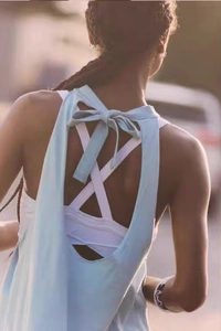Detail of light blue open back yoga top with tie-knot and white criss-cross sports bra