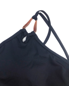 Détail d'un soutien-gorge de yoga noir avec anneau ambré et couture fine sur la bretelle