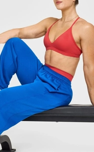 Detail eines roten Sport-BHs mit schmalen Trägern und blauer Kordelzug-Jogginghose