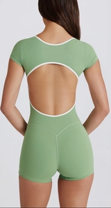 Detail of light green yoga romper showing the circular open back with white piping trim