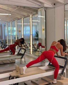 Red high-stretch yoga set featuring a halter sports bra and leggings on pilates equipment