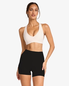 Close-up of ivory v-neck yoga top and black high-waisted shorts on a model
