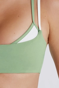 Gros plan d'un débardeur de yoga vert sauge avec coutures patchwork blanches et bretelles