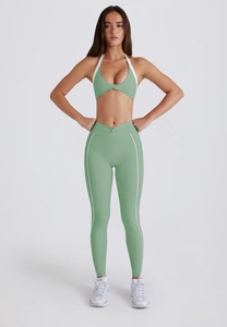Detail of green halter neck sports bra and high-waisted leggings set with white stripes