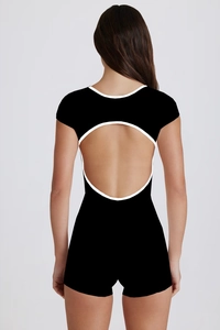 Rear view of black yoga bodysuit featuring a circular open back and white contrast trim