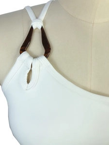 Détail d'un haut de yoga blanc asymétrique avec boucle en écaille de tortue sur l'épaule