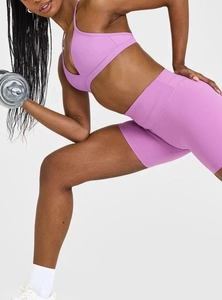 Detail eines lila Sport-BHs mit Kreuzgurten und passenden High-Waist-Fitness-Shorts
