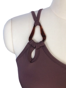 Détail de l'anneau en résine écaille et de la sangle nouée sur un haut de yoga marron
