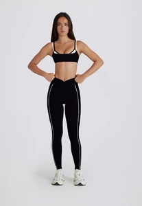 Détail d'un ensemble de sport noir avec débardeur col V et legging à taille haute et liseré