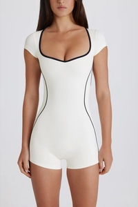 Close-up of white yoga bodysuit with square neck and black contrast piping detail