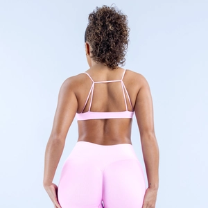 Detailansicht der Rückseite vom rosa Sport-BH mit Kreuzgurten und nahtlosen Fitness-Leggings