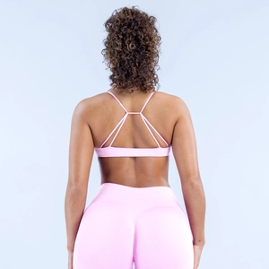 Detail der gekreuzten Träger am hellrosa nahtlosen Yoga-BH und der hochtaillierten Leggings