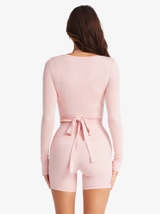 Vista posteriore del set yoga rosa con cardigan con fiocco e pantaloncini a vita alta