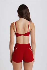 Détail de l'ensemble de yoga rouge avec nœud torsadé au dos et liseré sur le short