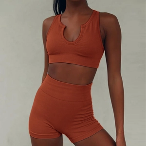 Close-up of seamless ribbed fabric texture on orange high-waist yoga shorts and tank top