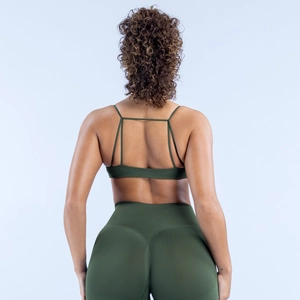 Detailansicht des nahtlosen dunkelgrünen Sport-BHs mit Kreuzgurten und High-Waist-Leggings