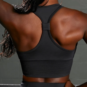 Detailed racerback design of seamless black sports bra with ribbed hem on model back