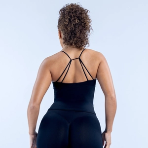 Détail des bretelles croisées sur débardeur de sport noir et legging de yoga