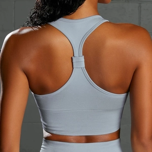 Detail of racerback yoga bra and high waist leggings against a grey industrial wall
