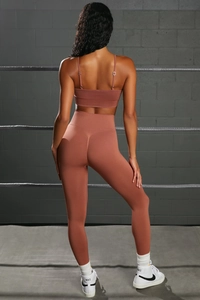 Detail view of seamless high-waist leggings and strap sports bra in terracotta red color