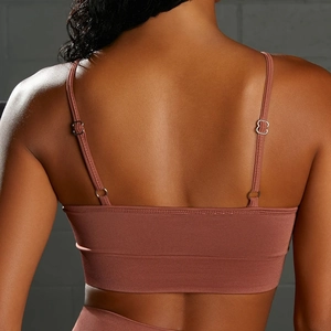 Detail of brick red sports bra with adjustable thin straps and seamless ribbed texture