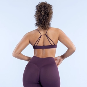Detail eines pflaumenfarbenen Sport-BHs und v-konturierte Leggings mit hohem Bund