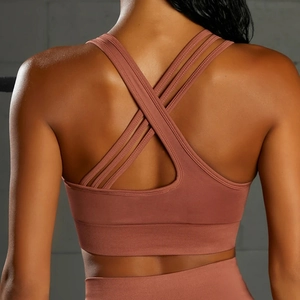 Detail view of brick red yoga bra with criss-cross back straps and wide ribbed hem support