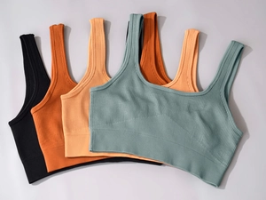 Nahaufnahme nahtloser gerippter Sport-BHs in Schwarz, Orange, Apricot und Salbeigrün