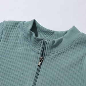 Détail d'un haut de yoga côtelé bleu sarcelle avec col montant et demi-zip métallique